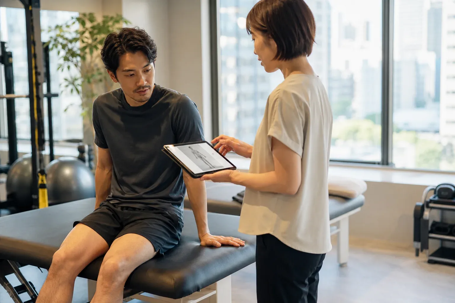 A clinician and an adult patient reviewing movement information in a bright rehabilitation studio